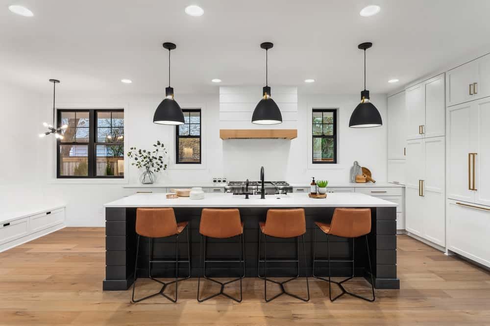 A modern kitchen with a long timber-topped island facing a wall of cabinetry